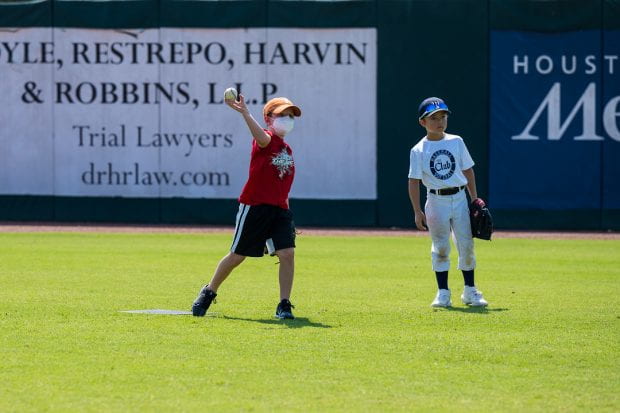 Children throwing a ball on a baseball field. 