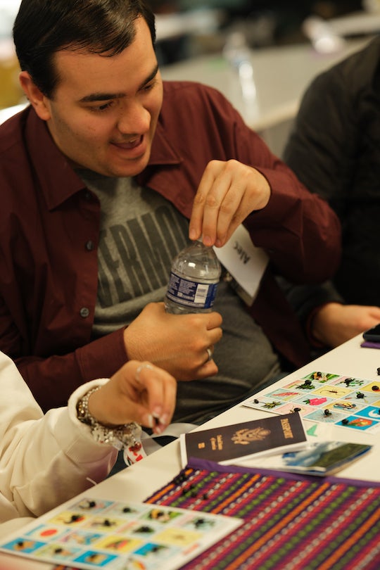 Grinning young adult with loteria card in front of him