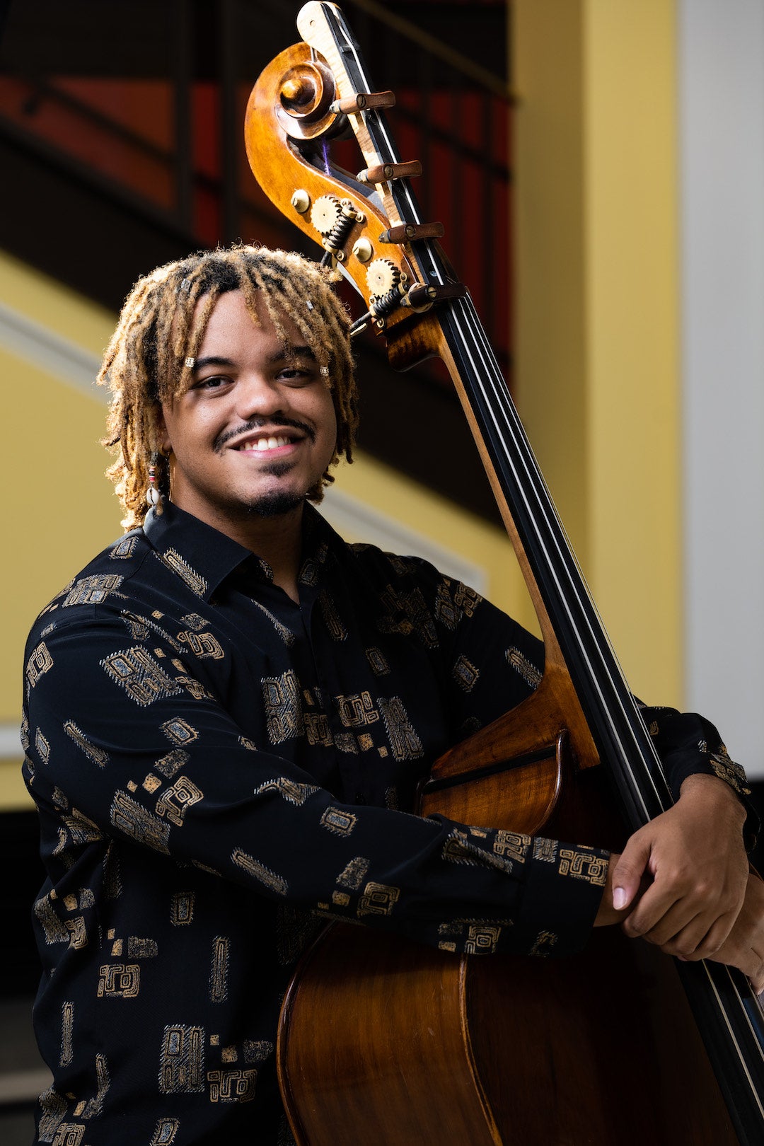 Christian Harvey standing with his double bass inside Brockman Hall for Opera lobby